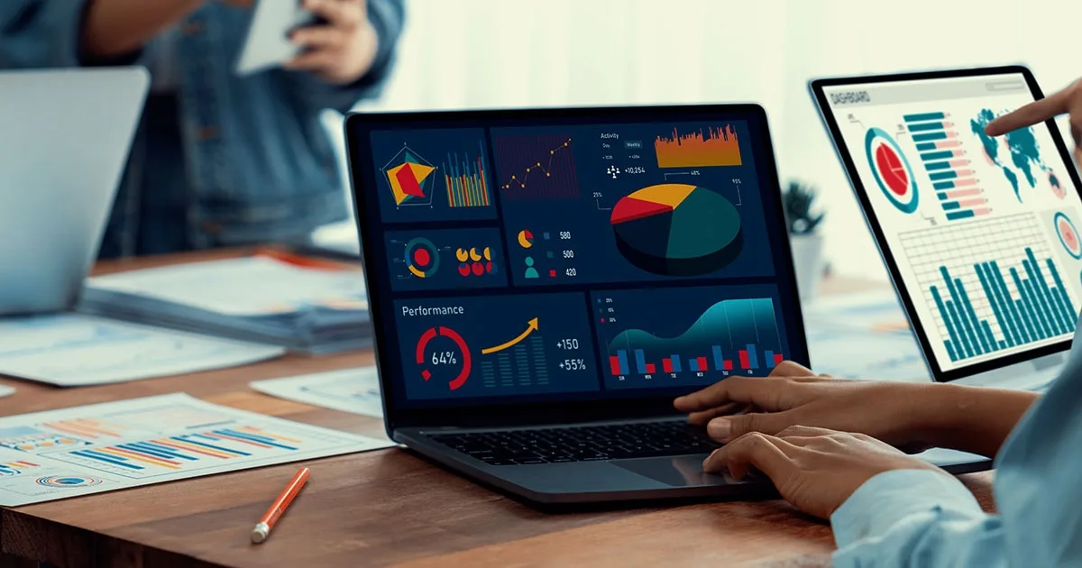 A person reviews data analytics insights on a laptop and tablet, displaying charts, graphs, and performance metrics, representing data-driven decision-making.